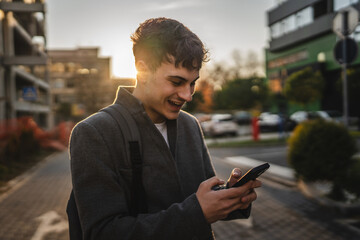 Fototapeta premium young adult man stand and use mobile phone on the street