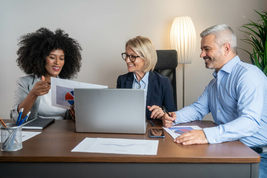 Casual meeting of smiling diverse business team analyzing financial data