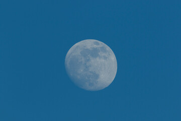 Bright full moon shines in a clear night sky over a serene landscape offering a tranquil view of...