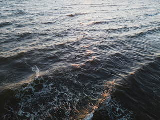 Sunset over the Baltic Sea. Drone view of endless waves, painted in golden hues by the setting sun.