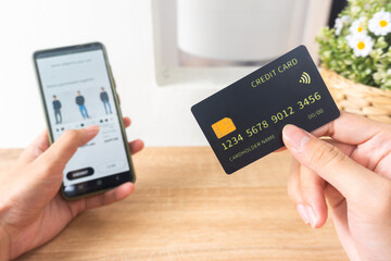 Pov first person holding black mockup credit card for online shop on smartphone at home