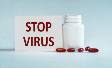 White Pill Bottle With Red Capsules and Stop Virus Message on Note