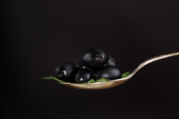 black olives in a spoon isolated on a black background
