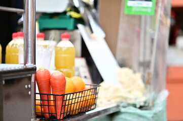 Fresh carrots sit ready for juicing at a traditional juice stall. These stalls often offer a variety of fruits like sugarcane, oranges, and pineapple, catering to all tastes.