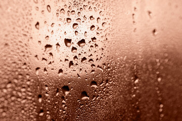 Drops on glass in glow of sunset close up, bokeh. Perfect Mocha brown background for your design and inspiration. Selective focus, defocus. Demonstrating color of 2025 year