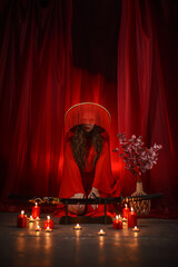 Beautiful young girl in a red kimono dress with a katana on red curtains background..