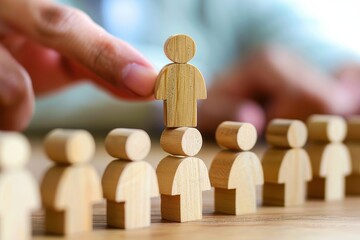 Leadership and Teamwork: A hand carefully places a wooden figure atop a line of others, symbolizing leadership, team building, and the importance of collaboration in achieving success.  