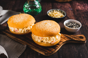 Salad burger with eggs, tomatoes, garlic and cheese on a board on a table