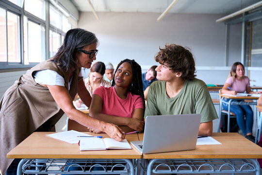 Young male teacher helping female student in class. The tutor helping his students by explaining the lesson and solving doubts. High quality photo