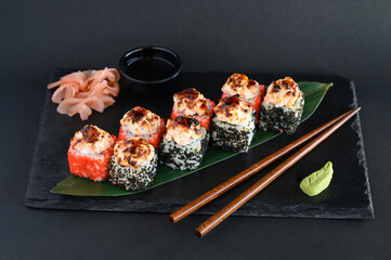 A set of sushi rolls on a wooden board and banana leaf, served with soy sauce, wasabi, ginger, and chopsticks. Perfect for an Asian restaurant menu.