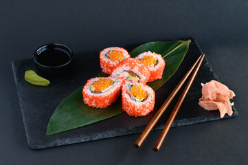 A set of sushi rolls on a wooden board and banana leaf, served with soy sauce, wasabi, ginger, and chopsticks. Perfect for an Asian restaurant menu.