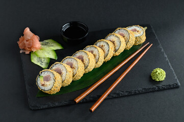 A set of sushi rolls on a wooden board and banana leaf, served with soy sauce, wasabi, ginger, and chopsticks. Perfect for an Asian restaurant menu.