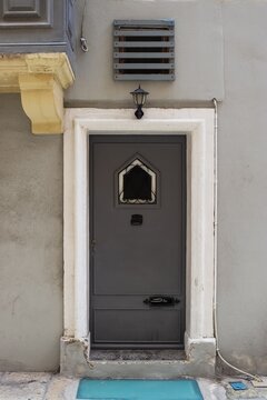 An old door dark grey to a flat in the alleyways of Maltas historic old towns.