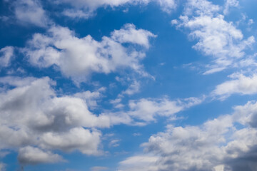 Bright clouds of varying shapes drift through the warm summer air.