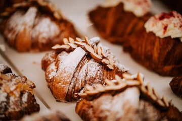 Freshly baked croissants on display at a bustling coffee shop in the morning light