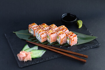 A set of sushi rolls on a wooden board and banana leaf, served with soy sauce, wasabi, ginger, and chopsticks. Perfect for an Asian restaurant menu.