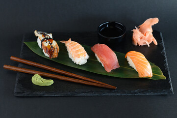 A set of sushi rolls on a wooden board and banana leaf, served with soy sauce, wasabi, ginger, and chopsticks. Perfect for an Asian restaurant menu.