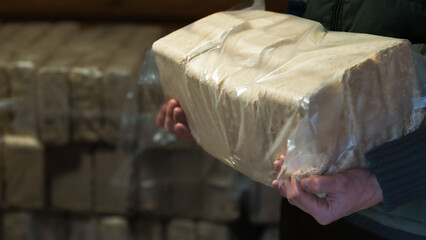 A pair of hands holding a pack of eco-friendly wood fuel briquettes, showcasing a sustainable...
