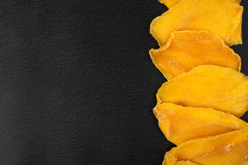 Candied mango petals on a dark background. Horizontal.