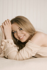 Obraz premium Portrait of smiling blonde woman with beautiful white smile in modern stylish beige interior