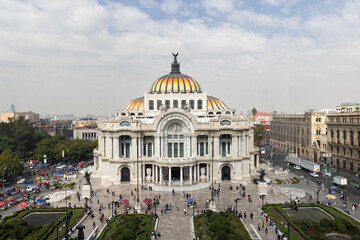 edificio de la ciudad de México conocido como el palacio de bellas artes, el cual es visto desde el aire, se ven personas pasando su día, conviviendo, tambien se ven comerciantes, trabajadores