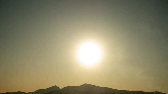 Sunrise Sun Moves Across the Blue Sky in Carpathian Mountains Hoverla and Petros In Time Lapse. Big and Bright Sun with Smoke from the Chimney in the Foreground