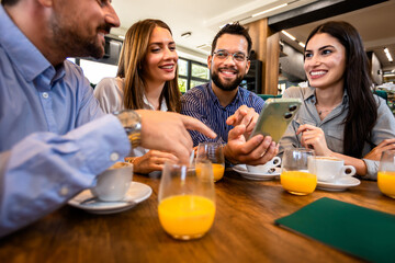 Group of friend met at the cafe. Looking at pictures on the phone. Having fun time together.