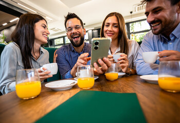 Group of friend met at the cafe. Looking at pictures on the phone. Having fun time together.