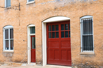 Wooden red front door and red gate to a brick house.