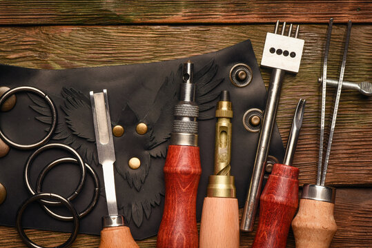 Leather and leatherworking tools on a leatherworker tanner workbench background.