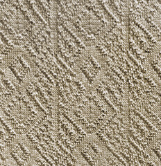Close up of knitted fabric in 3D diamond and stripes pattern carved on a light beige yellow wool fabric. Seamless background texture. 