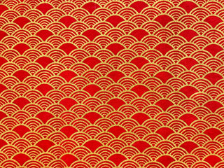 Printed fabric with Japanese fish scales or Chinese fish skin wave and curve pattern. Asian curved fan and fish scales pattern, in deep red and gold color. Seamless background texture.