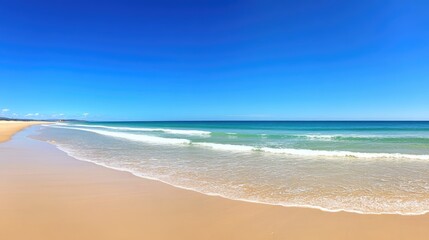 Fototapeta premium Sandy Beach Meets Turquoise Ocean Under Blue Sky