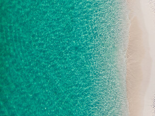 Crystal-clear turquoise waters meet soft sandy shore in this stunning aerial view of a tropical beach in the Bahamas.  