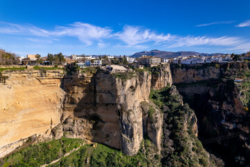 Cliff rocks and El Tajo gorge in the background supporting the village Ronda above with picturesque Andalusian scene in countryside of Spain