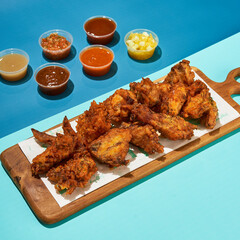 a delicious stacked of crispy fried chicken wings with a variety of sauce on a colorful background