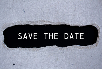 Save the date message written on ripped torn gray paper with black background. Conceptual save the...