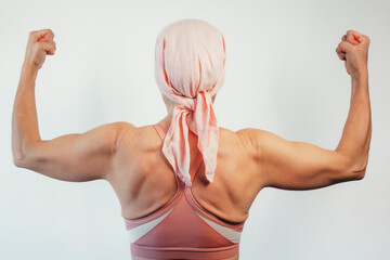 Woman with pink headscarf, view from behind, cancer awareness.