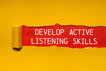 Develop active listening skills message written on ripped torn yellow paper with red background....