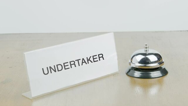 Undertaker Office or Room with Hand Ringing The Bell on Desk or Table Multiple Times