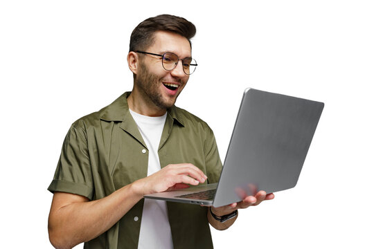 Excited man using laptop with joy in a modern workspace setting while wearing casual attire