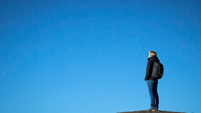 Person with Backpack Gazing at a Vast Blue Sky