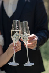 Wedding glasses with white wine in hands bride and groom