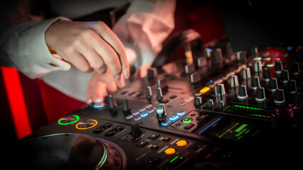 Close up DJ plays live set and mixing music on turntable console in the night club. Disc Jokey Hands on a sound mixer station at club party. DJ mixer controller panel for playing music and partying.