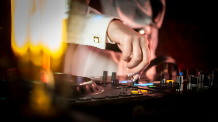Close up DJ plays live set and mixing music on turntable console in the night club. Disc Jokey Hands on a sound mixer station at club party. DJ mixer controller panel for playing music and partying.