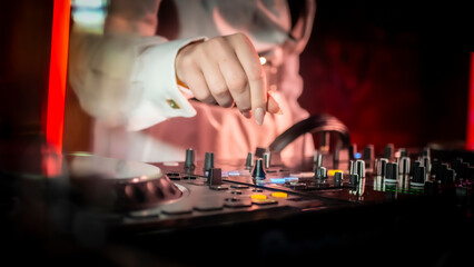 Close up DJ plays live set and mixing music on turntable console in the night club. Disc Jokey Hands on a sound mixer station at club party. DJ mixer controller panel for playing music and partying.