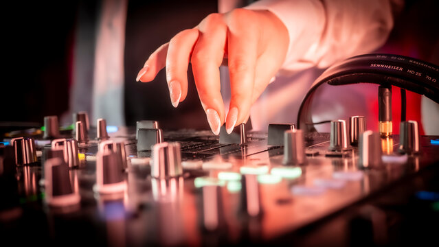 Close up DJ plays live set and mixing music on turntable console in the night club. Disc Jokey Hands on a sound mixer station at club party. DJ mixer controller panel for playing music and partying.