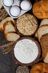 fresh bread and assortment of baked goods on dark background, vertical top view