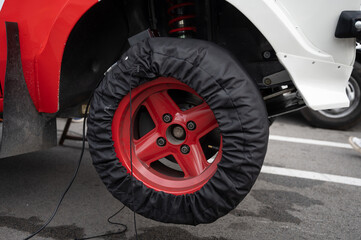 Detail of the electric competition tire warmer blanket on the wheel of a classic rally car