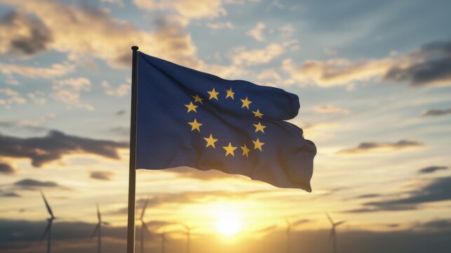European Union flag waving against a vibrant sunset with wind turbines in the background